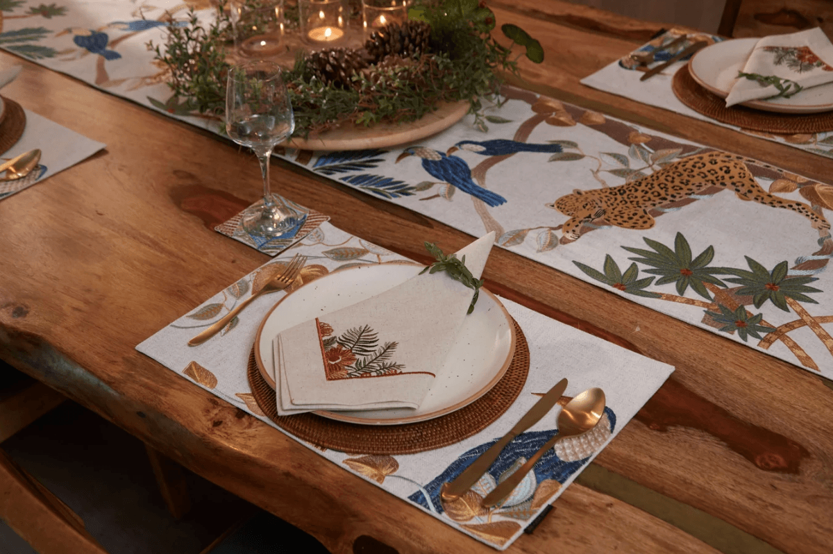 A considered table setting with embroidered linen, ceramic plates and glassware