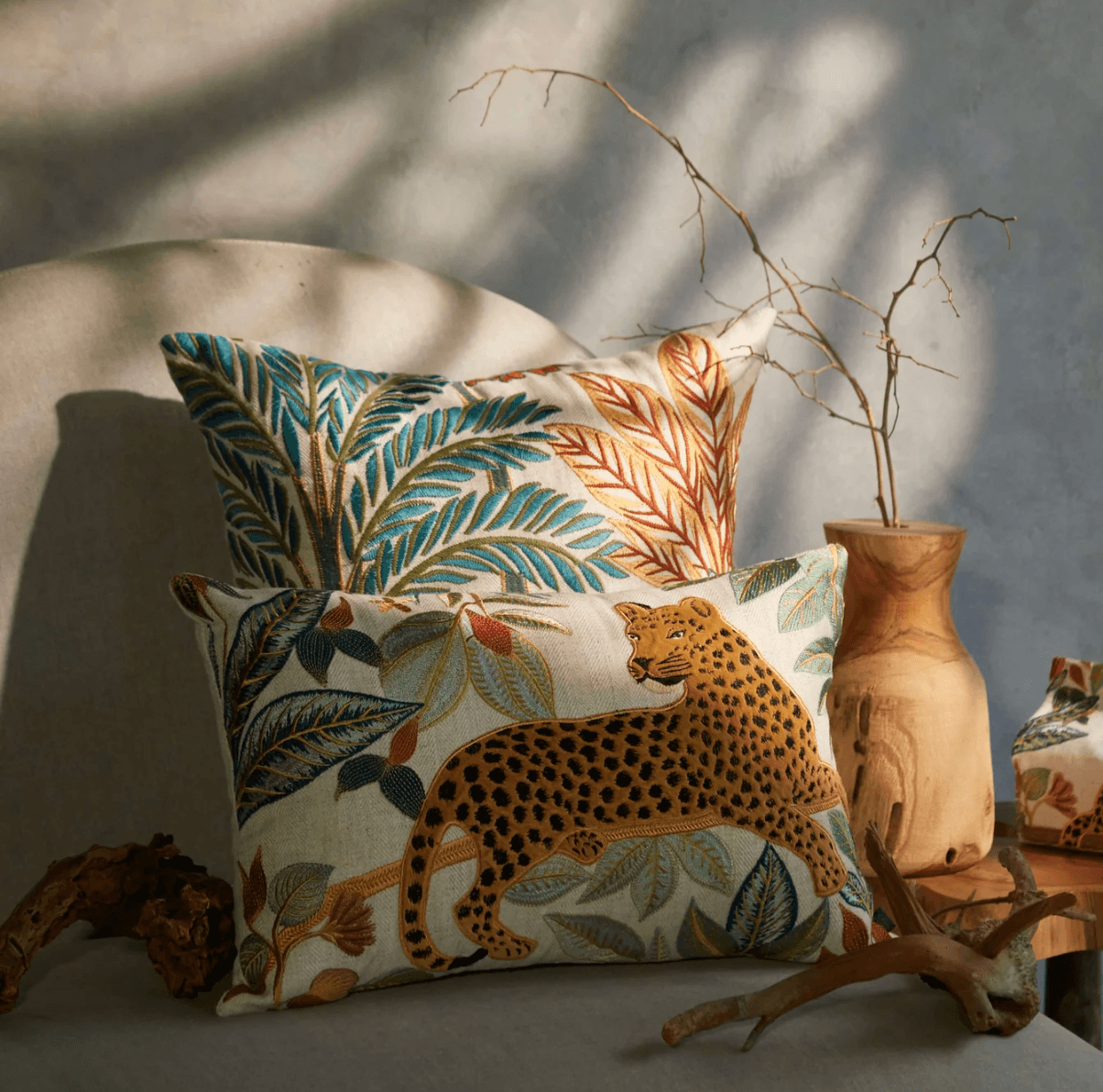 Embroidered botanical cushions layered on a softly textured sofa